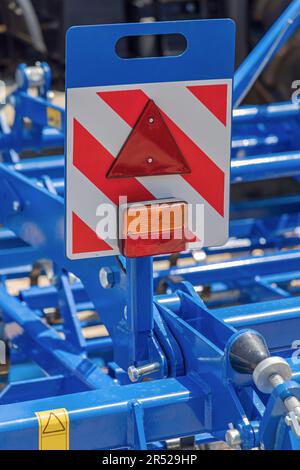 Feux de direction triangulaires réfléchissants de sécurité à l'extrémité arrière de la remorque agricole bleue Banque D'Images