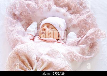 Adorable nouveau-né bébé fille dormant dans un sac de couchage à enveloppe chaude rose Banque D'Images