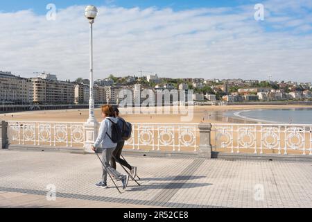 Femmes marchant, vue de deux amies marchant ensemble sur une promenade le long de la plage de San Sebastian, côte du nord de l'Espagne Banque D'Images