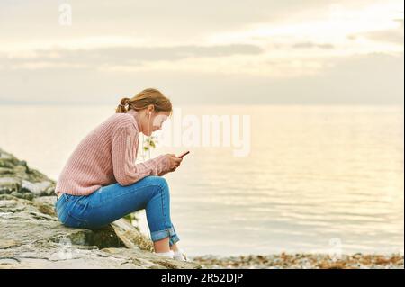 Portrait en plein air d'une jeune adolescente écoutant de la musique près du lac ou de la mer, image prise à Lausanne, Suisse Banque D'Images