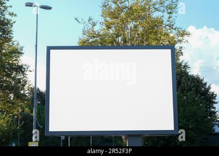 Panneau d'affichage publicitaire vierge Affichage panneau d'affichage maquette extérieur avec arbres et ciel bleu nuageux fond. Arrière-plan de bannière de panneau d'affichage blanc dans la ville. Banque D'Images