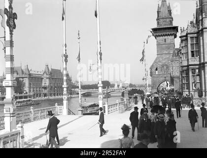 Personnes marchant dans une rue pavée de Paris. Avec pont Alexandre III en arrière-plan. Début du 20th siècle. Ancienne photo numérisée. Banque D'Images