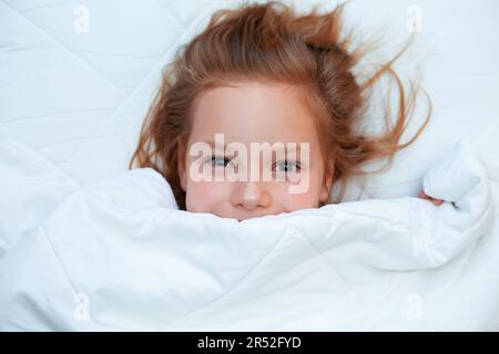 Portrait d'une petite fille dormant au lit à la maison Banque D'Images
