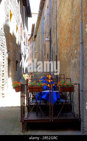 Italie, Italie, Marche, Urbino, centre-ville, vieille ville, ruelle étroite avec table de restaurant, table de restaurant avec chaises sur la ruelle Banque D'Images