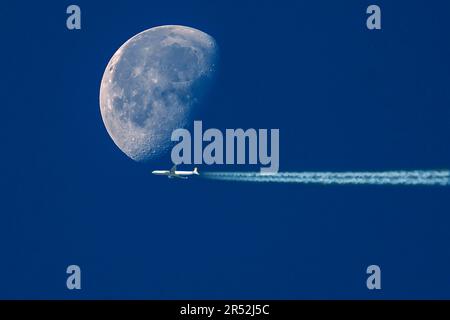 Avion avec des contrailles devant la lune en déclin dans le ciel tôt le matin, Bavière, Allemagne Banque D'Images