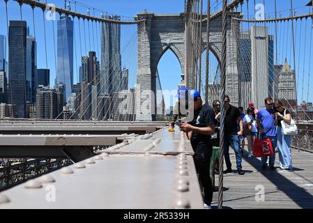 Visiteurs sur la passerelle piétonne du pont de Brooklyn avec les gratte-ciel de Manhattan en arrière-plan. Banque D'Images