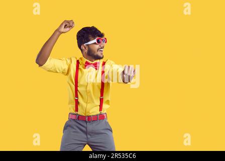 Joyeux drôle d'Indien dans la tenue de fête dansant style gangnam isolé sur fond jaune Banque D'Images