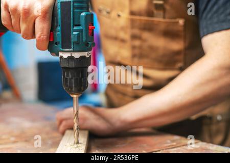 Menuisier fore un trou dans une planche en bois avec une perceuse électrique Banque D'Images