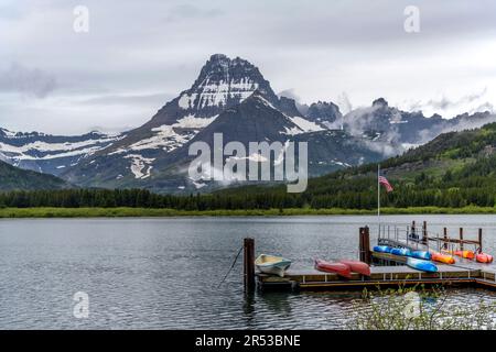 Mise à l'eau du bateau au lac SwiftCurrent - Un des États-Unis Drapeau volant au-dessus de l'embarcadère au lac SwiftCurrent, le matin du printemps. Nombreux glaciers, parc national des Glaciers. Banque D'Images