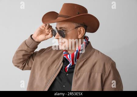 Cowboy mature dans des lunettes de soleil sur fond clair Banque D'Images