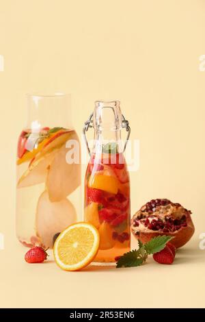 Bouteilles d'eau infusée avec différentes tranches de fruits sur fond beige Banque D'Images