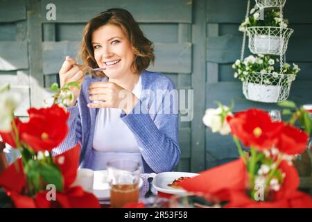 Portrait d'une jeune femme heureuse mangeant du yaourt à la table, petit déjeuner de pâques Banque D'Images