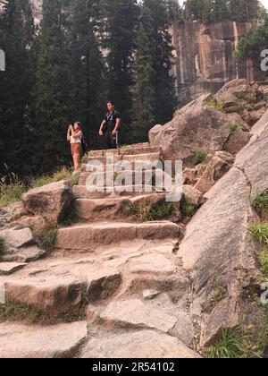 Un jeune couple fait une pause sur le sentier de randonnée escarpé du parc national de Yosemite pour prendre une photo de la vue Banque D'Images