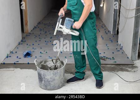 Homme mélangeant de l'adhésif pour carreaux à l'intérieur, vue rapprochée Banque D'Images