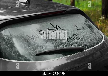 Phrase Wash Me écrit sur la fenêtre sale de voiture à l'extérieur, gros plan Banque D'Images