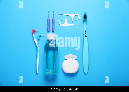 Fil dentaire et différents produits de soins dentaires sur fond bleu clair, plat Banque D'Images