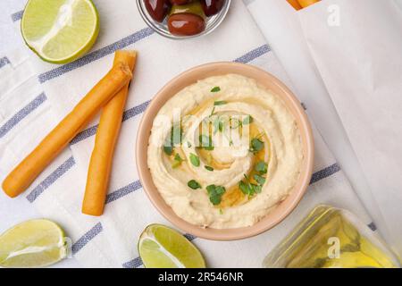 Délicieux houmous avec bâtonnets de graissini, citron vert et olives sur table gris clair, plat Banque D'Images