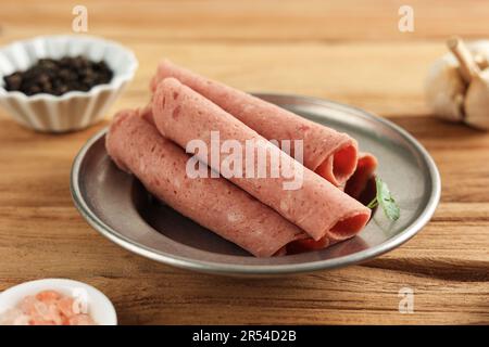 Fines tranches de saucisses de bœuf salami fumées sur une assiette rustique Banque D'Images