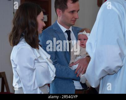 Les parents tenant leur petite fille dans une église prête pour le baptême Banque D'Images