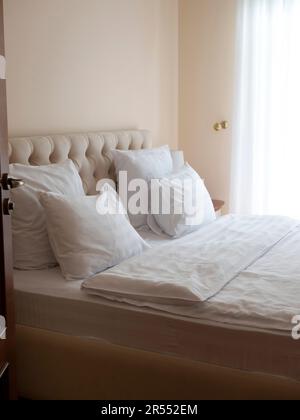 Coin couchage avec lit moderne recouvert de linge blanc neige. Chambre à coucher remplie de lumière, foyer sélectif Banque D'Images