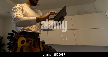 Un travailleur regarde une tablette. Maître avec une tablette électronique dans ses mains Banque D'Images