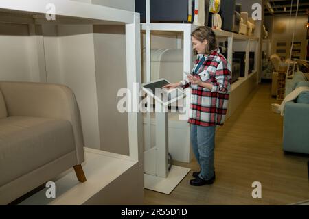 Une femme au téléphone utilise un kiosque en libre-service dans le centre commercial. Photo de haute qualité Banque D'Images