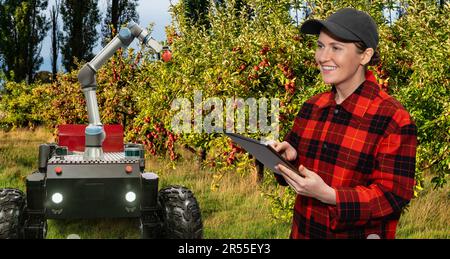 L'agriculteur commande une robot-récolteuse autonome avec des pommes de récolte à bras robotisé sur une ferme intelligente. Concept. Photo de haute qualité Banque D'Images