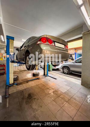 Voiture sur ascenseur, vue en angle bas. Concept d'atelier de réparation de voiture : arrière-plan intérieur de service automobile avec voitures sur ascenseur. Coûts de maintenance. Accident de voiture Banque D'Images