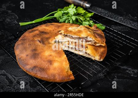 Tarte d'ossète cuite avec de la viande de boeuf et des herbes. Arrière-plan noir. Vue de dessus. Banque D'Images