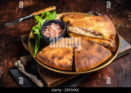 Tarte traditionnelle d'ossète coupée en tranches sur une assiette. Arrière-plan sombre. Vue de dessus. Banque D'Images