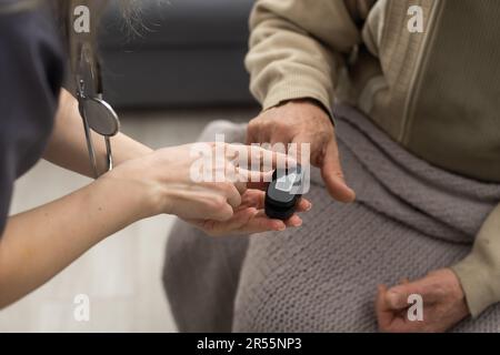 Mesure du niveau d'oxygène et de la fréquence de pouls à l'aide d'un oxymètre de pouls portable - un homme surveille sa santé Banque D'Images