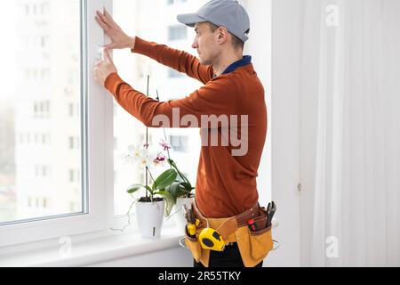 maître en gants de protection, changer une fenêtre à double vitrage dans une fenêtre en plastique. Banque D'Images