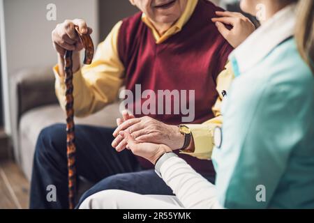 L'infirmière soignante à domicile aide le vieil homme à son domicile. Soutien professionnel de la santé pour les personnes âgées. Banque D'Images