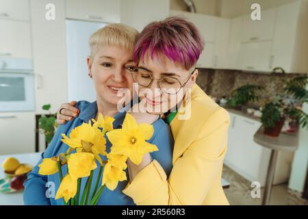 Un moment réconfortant : non-Binary Daughter présente des fleurs d'anniversaire à mère Banque D'Images