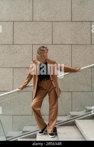 Portrait d'une femme d'affaires en costume de pantalon debout sur des marches à l'extérieur d'un bâtiment, Biélorussie Banque D'Images