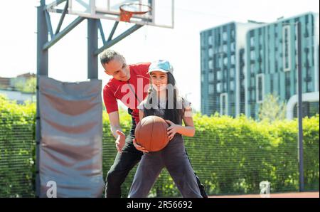 Père et fille jouant au basket-ball ensemble sur des jeux pour enfants Banque D'Images