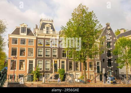 Pays-Bas. Façades de bâtiments typiques sur une rue d'été à Amsterdam. Personnes, bicyclettes et voitures sur le quai du canal Banque D'Images