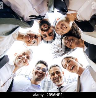 Des hommes d'affaires variés et gais se tenant dans un cercle dans la rue. Vue d'ensemble d'une équipe de direction heureuse et réussie qui forme un caucus Banque D'Images