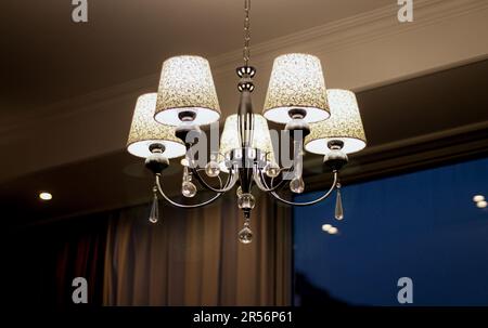 Magnifique lustre de style classique accroché au plafond de la chambre d'hôtel Banque D'Images