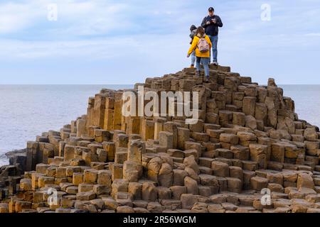 Touristes se tenant sur les formations de basalte à la chaussée des géants, Bushmills, comté d'Antrim, Irlande du Nord, un célèbre site classé au patrimoine mondial de l'UNESCO. Banque D'Images