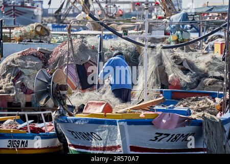 Mahdia, Tunisie, 29 janvier 2023: Le pêcheur trie les filets en nylon en filigrane sur le petit bateau de pêche après la prise. Banque D'Images