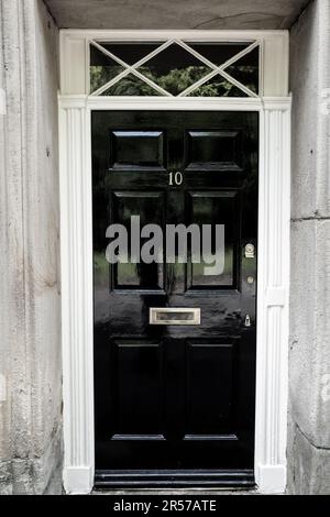 Porte avant en panneau de bois peint en noir avec le numéro 10 et cadre de porte en bois blanc. Banque D'Images