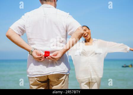 Homme tenant l'anneau de mariage à sa petite amie sur la plage avec le soleil Banque D'Images
