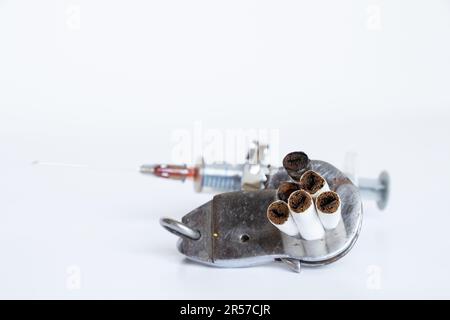 Une seringue et des cigarettes sont menottées sur un fond blanc, la toxicomanie, une mauvaise habitude Banque D'Images