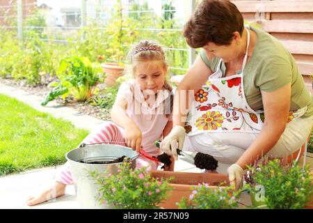 Vieille Femme et enfant fleurs de replantation pour une meilleure croissance Banque D'Images