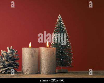 Deux bougies de l'Avent qui brûlent sur un fond rouge avec une décoration de Noël Banque D'Images