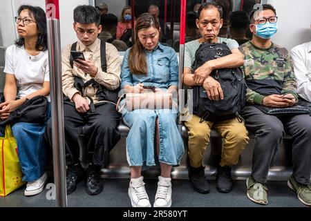 Personnes utilisant leur smartphone sur Un train MTR, Hong Kong, Chine. Banque D'Images