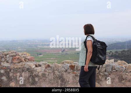 Vue arrière d'une femme adulte active voyageur avec un sac à dos se tient sur la colline après la randonnée en haut admire paysage appréciant la liberté. Un mode de vie sain à la retraite Banque D'Images
