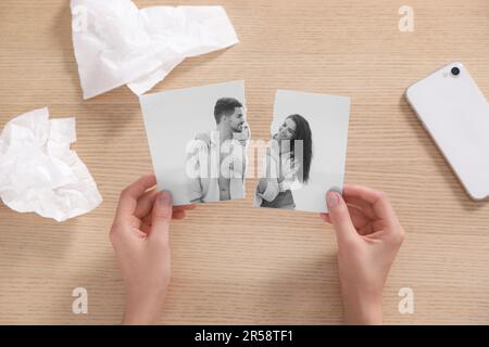 Divorce et rupture. Femme tenant des parties de photo noire et blanche déchirée à la table, vue de dessus Banque D'Images