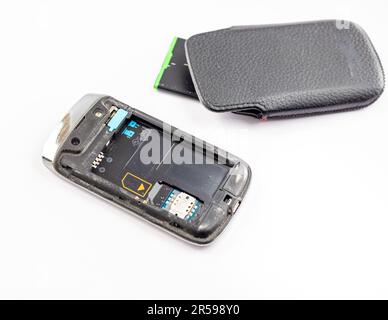 Couvercle arrière du téléphone portable et batterie retirés avec un étui en cuir noir sur fond blanc isolé Banque D'Images